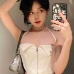 Malaysia Escort Girl Stylish young woman in a white corset top takes a selfie. Sex Service Kuala Lumpur
