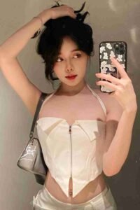 Malaysia Escort Girl Stylish young woman in a white corset top takes a selfie. Sex Service Kuala Lumpur