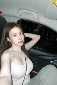 Malaysia Escort Girl Woman in a car wearing a white tank top and gray sweatpants. Sex Service Kuala Lumpur