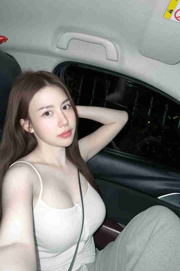 Malaysia Escort Girl Woman in a car wearing a white tank top and gray sweatpants. Sex Service Kuala Lumpur