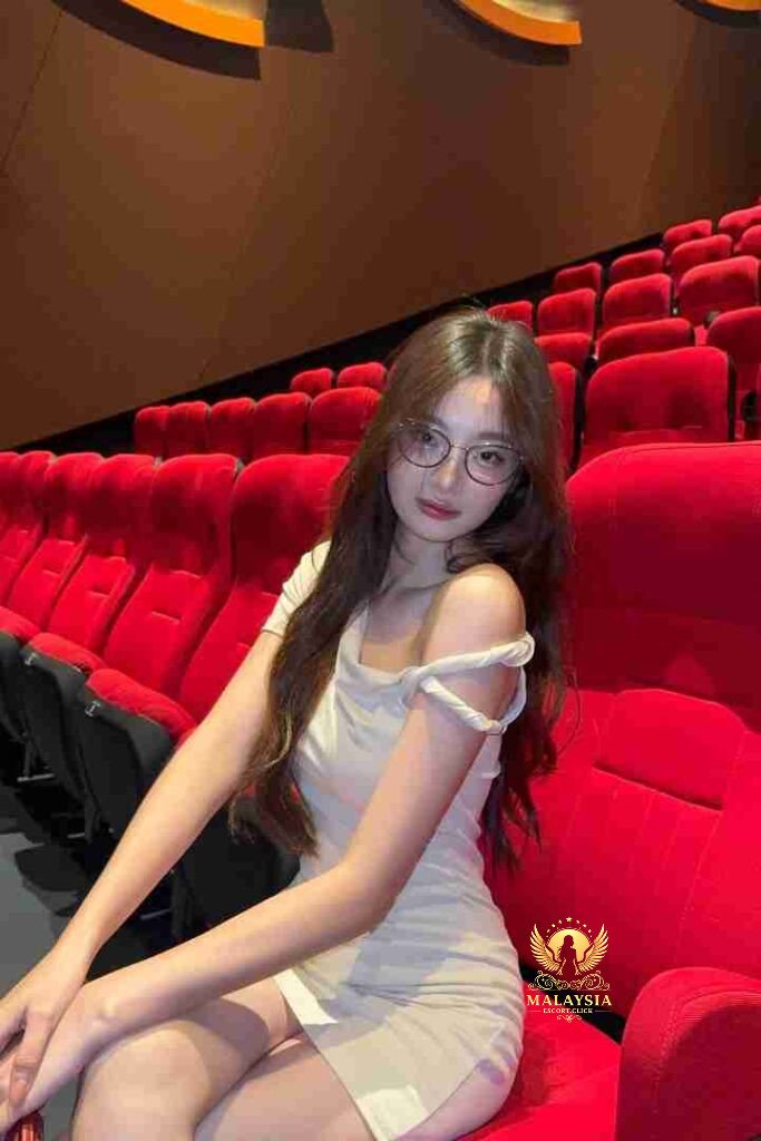 Asian woman in dress sitting in theater seat.