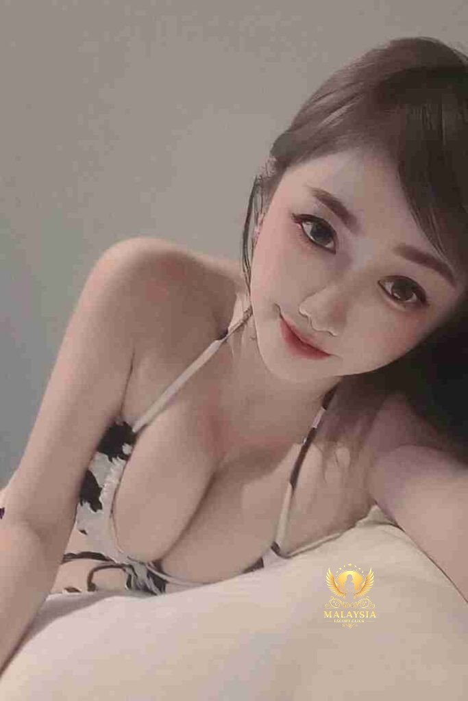 Attractive Asian woman in lingerie lying on a pillow, smiling.