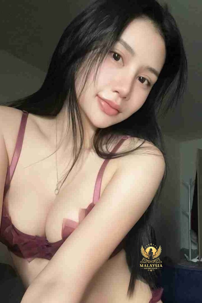 Attractive Asian woman with long black hair and a maroon bra, looking at the camera.