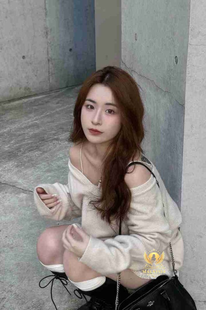 Asian woman in off-shoulder sweater crouching, wearing knee-high socks. KL call girl.