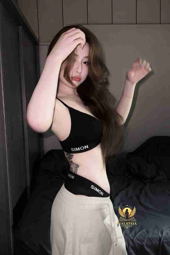 Asian woman in sports bra and pants posing indoors.