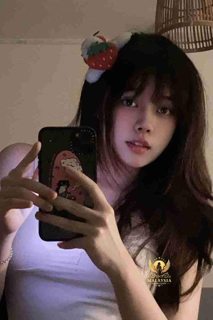 Asian woman with strawberry hair clip taking selfie with phone case featuring cartoon cat and girl.