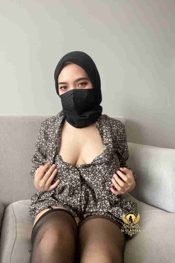 Curvy Khayla in hijab, floral dress, and stockings on sofa.