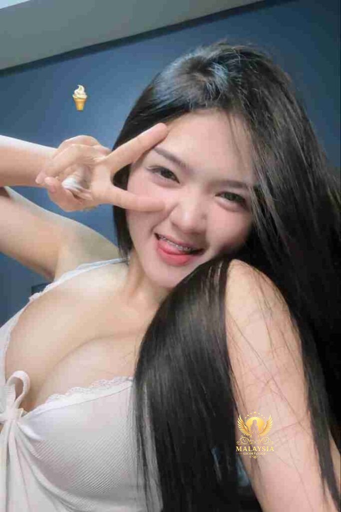 Alluring Thai woman, Kiera, with long black hair, smiling and making a peace sign. Braces visible.