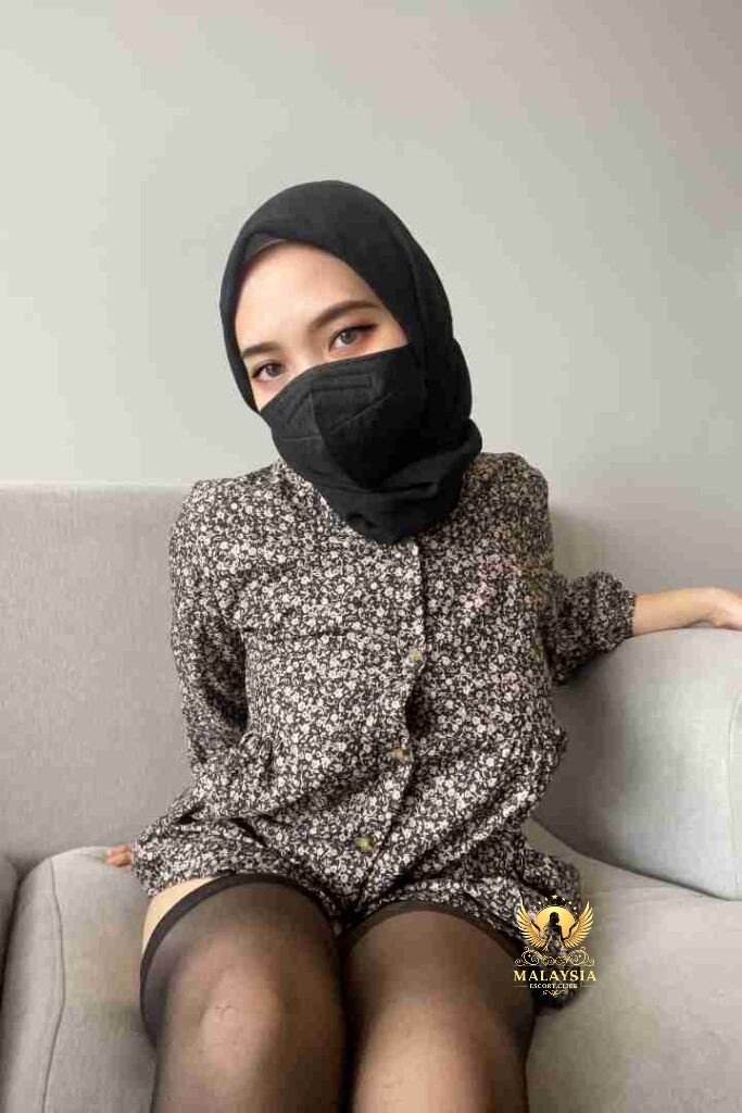 Malaysia Escort Girl Woman in gray dress with slit, black purse, and white sandals posing on a bench. Sex Service Kuala Lumpur