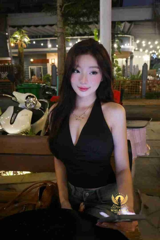 Ella, Vietnamese woman in black top, holding phone outdoors at night.