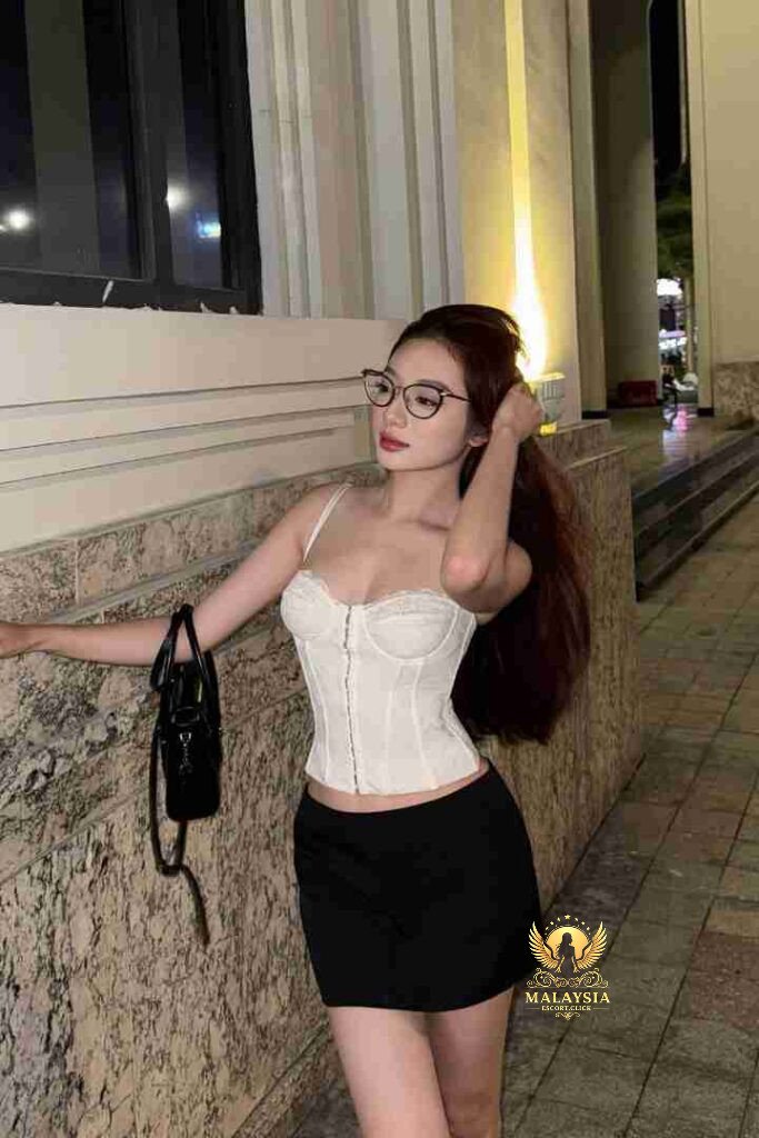 Vietnamese woman in corset and skirt, wearing glasses. KL escort vibe.