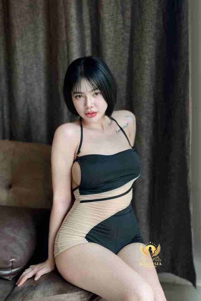 Attractive woman in stylish black and beige swimsuit sitting indoors. Short black hair, confident pose.