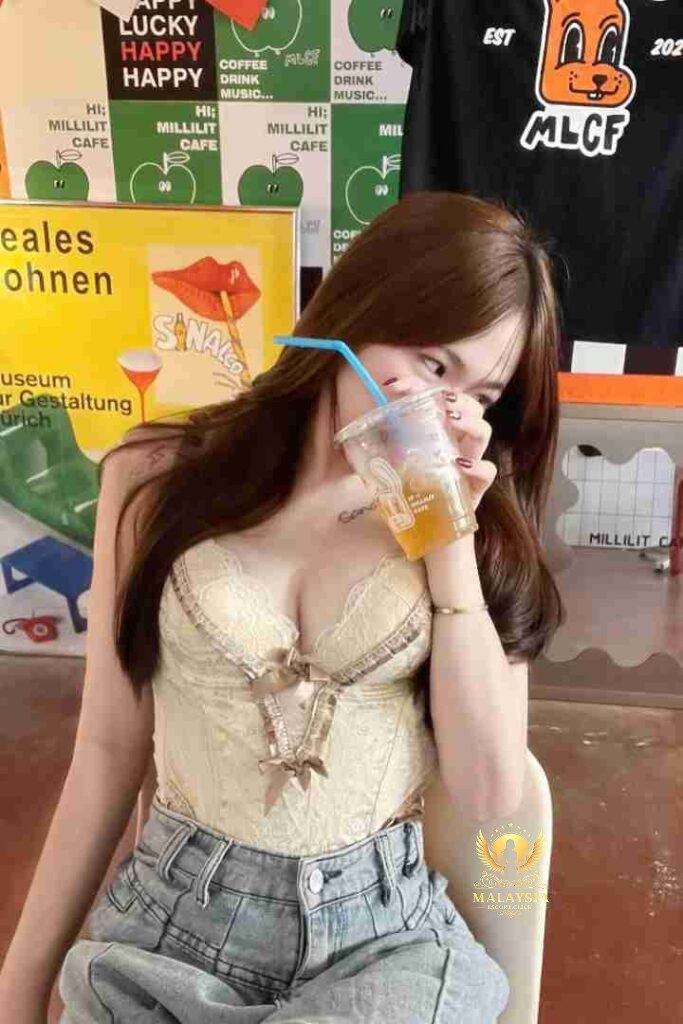 Woman drinking iced drink in cafe with "Millilit Cafe" signs visible.