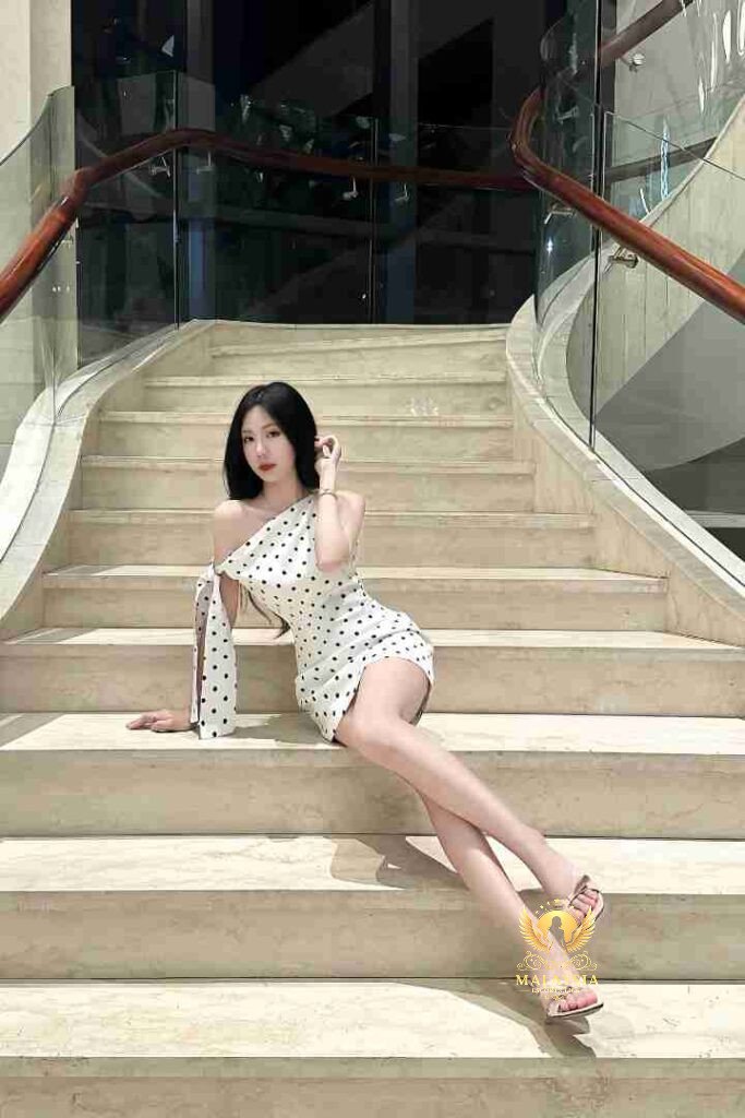 Woman in polka dot dress sitting on marble stairs.